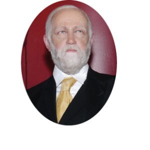 Presidential wax figure of a man with a white beard, donned in a black suit, white shirt, and yellow tie, set against a dark red backdrop. Presidential wax figure of a man with a white beard, donned in a black suit, white shirt, and yellow tie, set against a dark red backdrop.