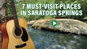 A scenic view of a river surrounded by lush greenery in Saratoga Springs, with a large rock in the water. An acoustic guitar rests on the left side. Text overlay reads, 7 Must-Visit Places in Saratoga Springs with a play button icon.