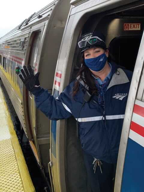 Amtrak conductor Cheri VanNess waving from train entrance