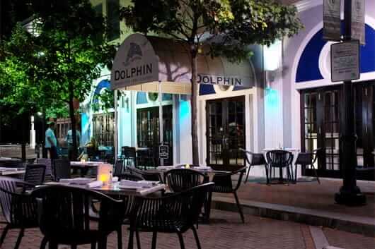 Outside eating area of Dolphin Bar at night with front view of restaurant.