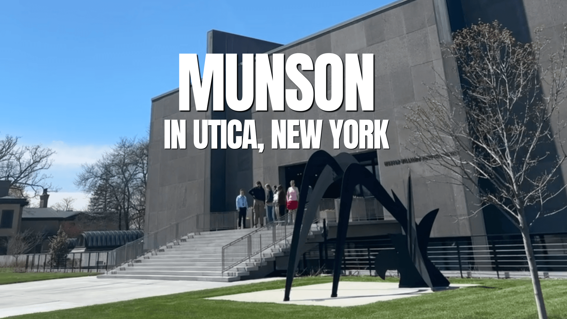 A group of people stand at the entrance of the Munson museum in Utica, New York, with a modern black metal sculpture on the lawn and bold text over the image reading Munson in Utica, New York, perfect for a video template or template page.