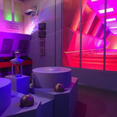 A futuristic, colorful room with geometric shapes, control panels, and glowing pink and purple lights, resembling a sci-fi spaceship or laboratory setting inspired by the iconic Star Trek Original Series Set.