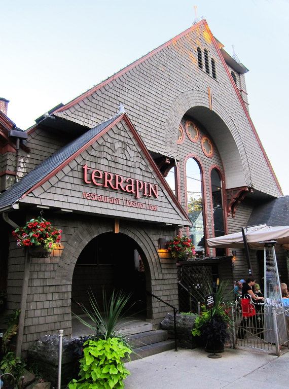 Terrapin Restaurant bistro bar in a building with arched windows, wooden shingles, and flowers hanging by the entrance. People are dining outside, enjoying the welcoming ambiance of Terrapin Restaurant.