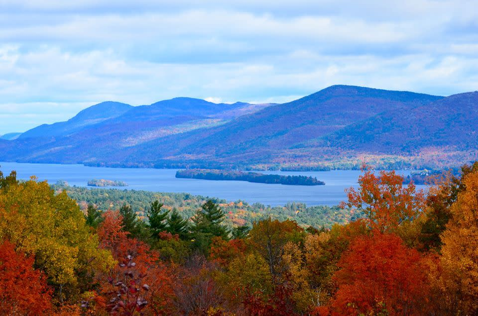 A view of an Adirondack Craft Beverage Trail lake surrounded by mountains and autumn-colored trees.